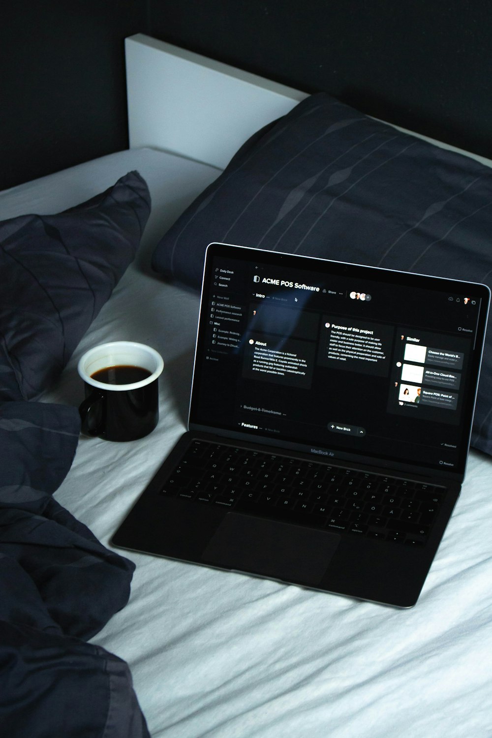 白いベッドの上の黒いラップトップコンピュータ