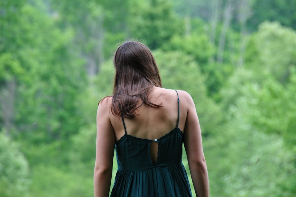 woman in blue spaghetti strap dress standing on green grass field during daytime