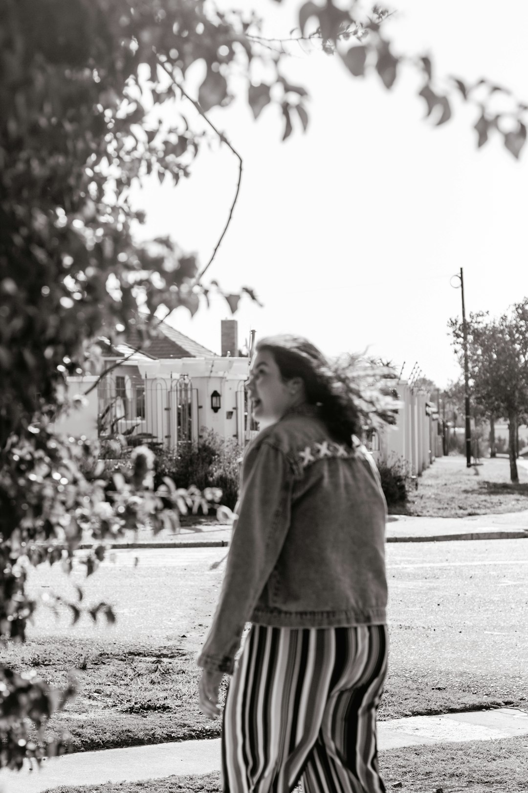 grayscale photo of girl in coat standing on road