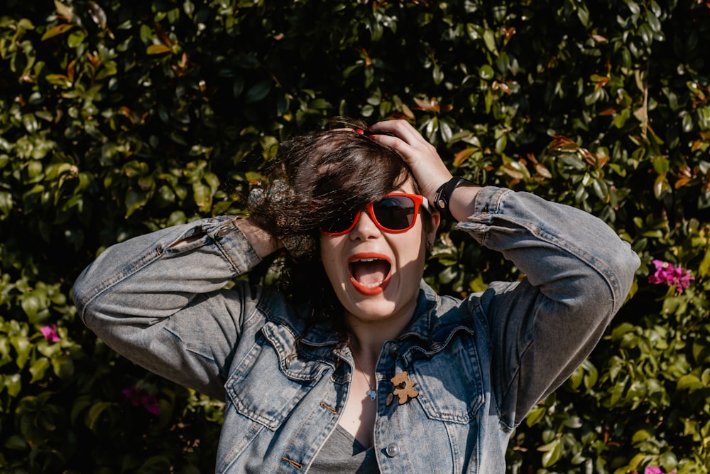 woman in blue denim jacket and red framed sunglasses