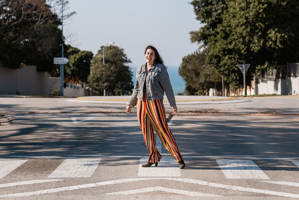 woman in black jacket and orange and black striped skirt standing on gray concrete road during