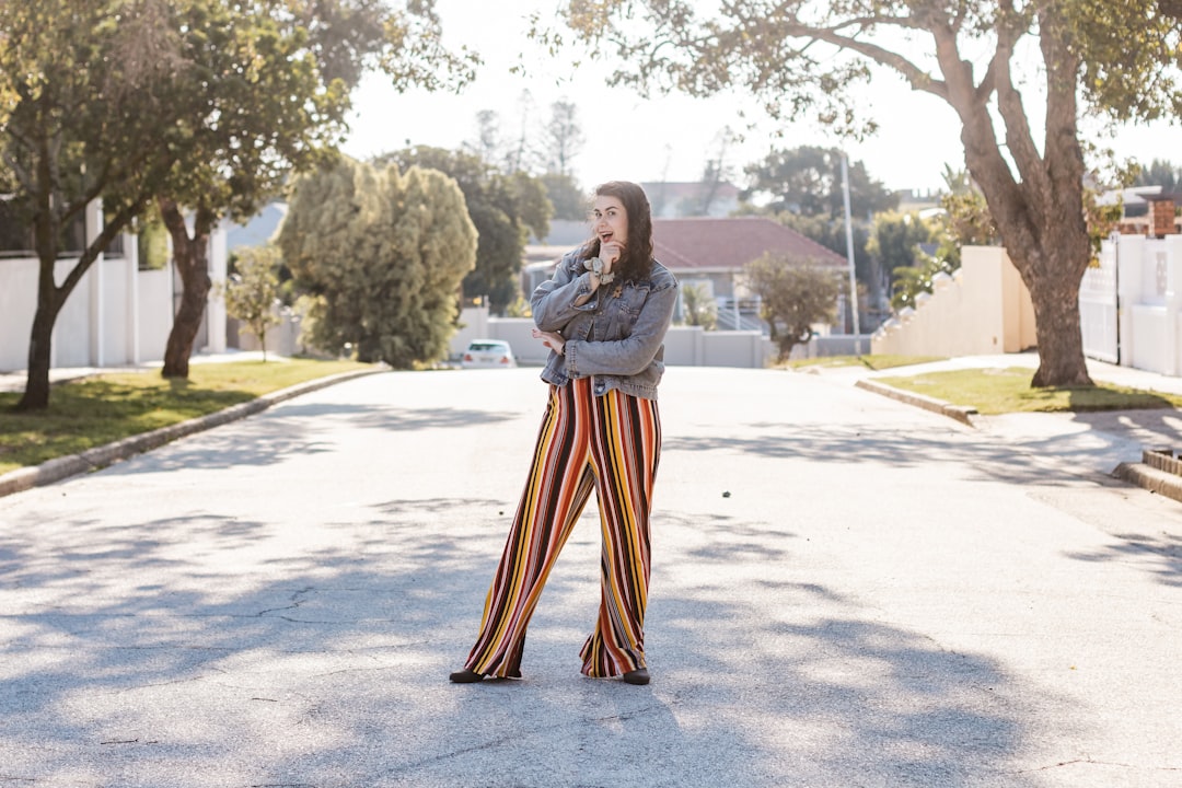 woman in white long sleeve shirt and orange and yellow skirt standing on gray concrete road