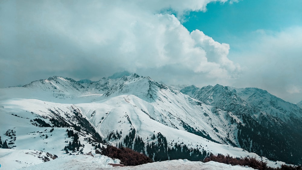 Schneebedeckter Berg tagsüber unter weißen Wolken