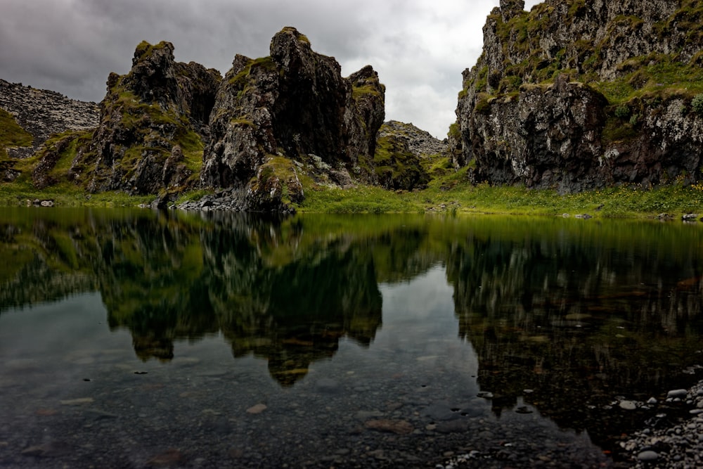 brown rock formation on body of water under cloudy sky during daytime