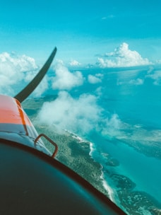Airplane flying over turquoise ocean and islands.