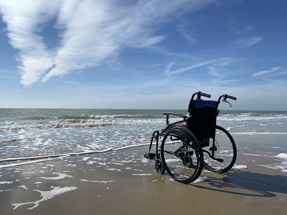 sedia a rotelle nera e grigia sulla spiaggia durante il giorno