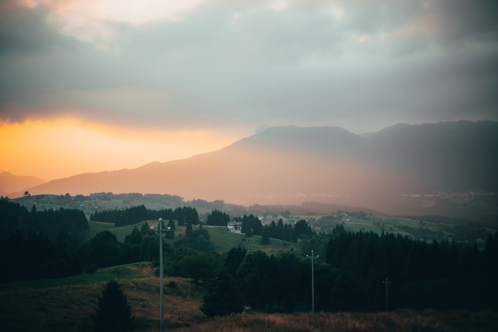 green trees and mountains during sunset