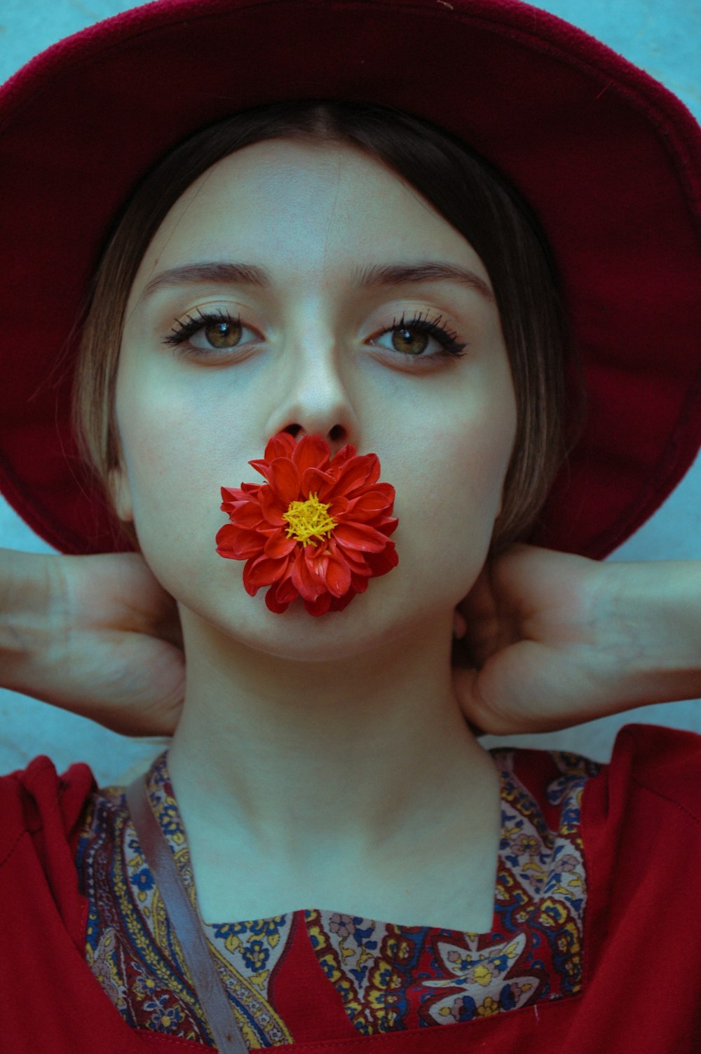 woman in red and white floral shirt holding red flower