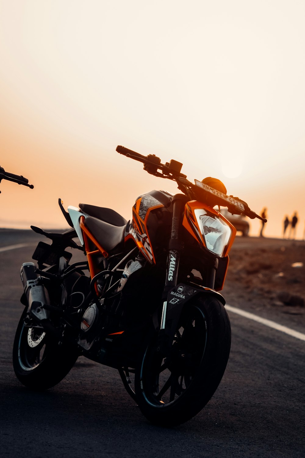 motocicleta negra y roja en la carretera durante la puesta del sol