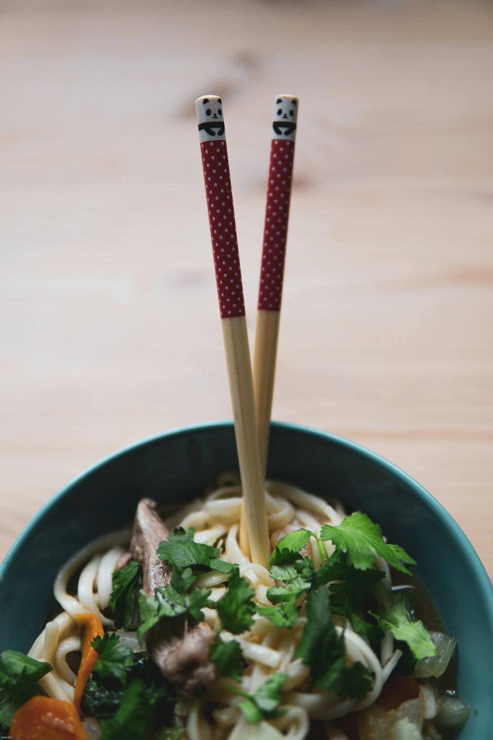 green and white ceramic bowl with brown chopsticks