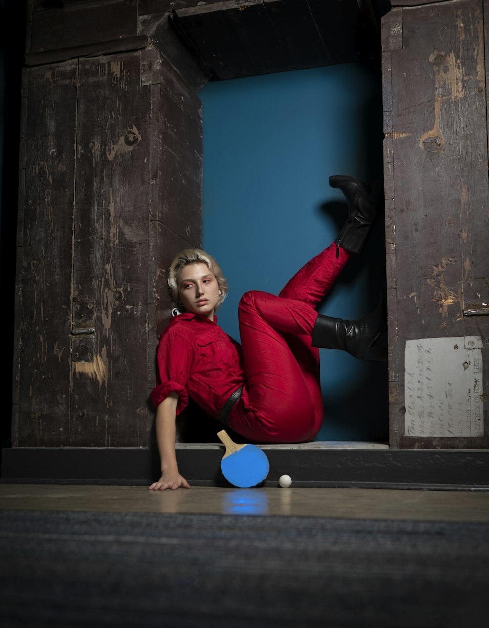woman in red long sleeve shirt and black pants lying on floor