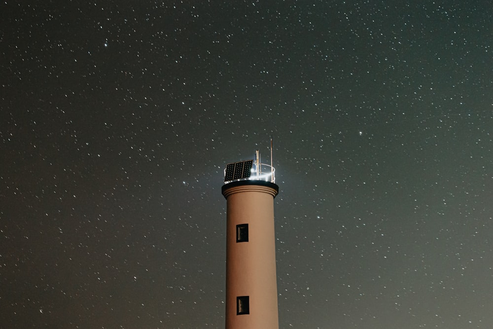 brown and white lighthouse under black sky