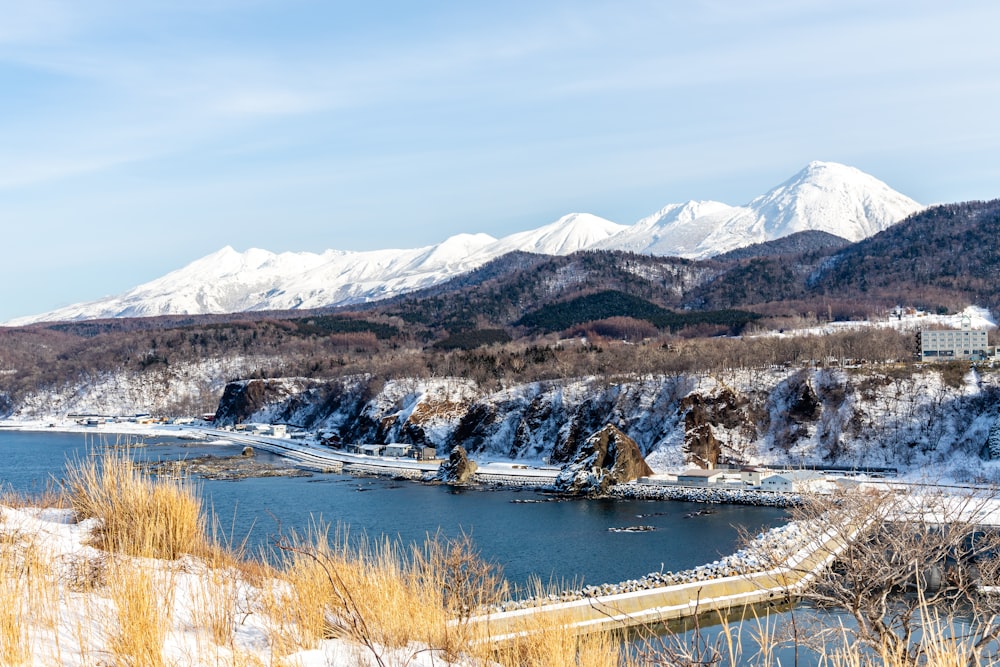 brown grass field near lake and snow covered mountains during daytime