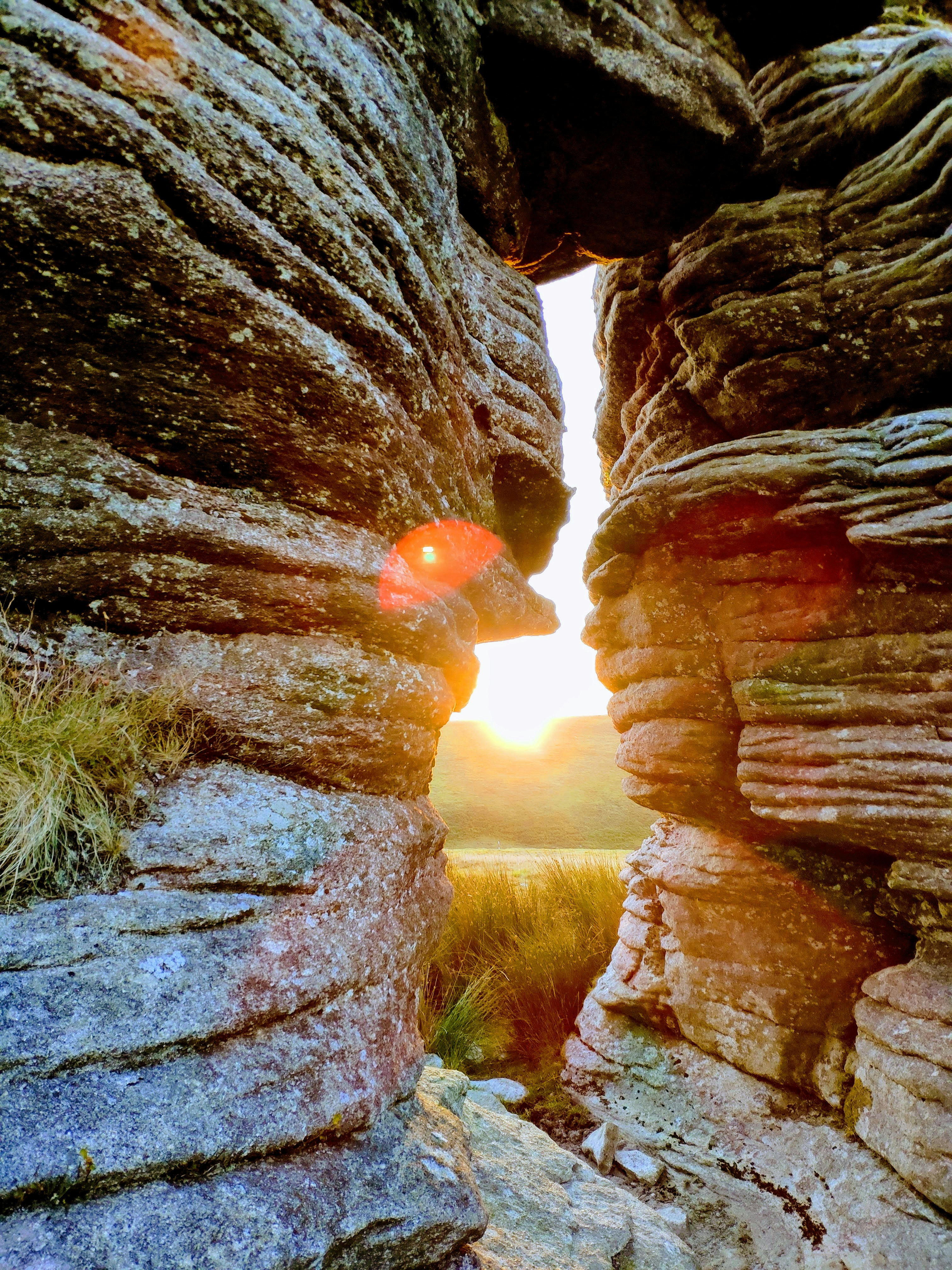Stylised view of the sunset through the "Thurlstone" of Watern Tor, with aggressive lens flare seen.