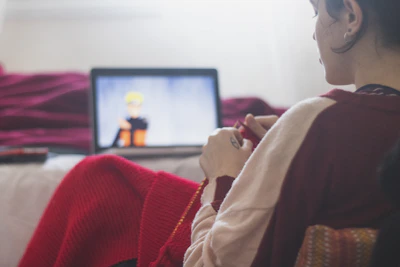 A smiling student watching crochet lessons on a tablet at home.