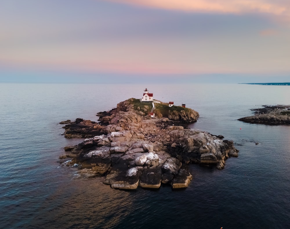 person sitting on rock formation near body of water during daytime