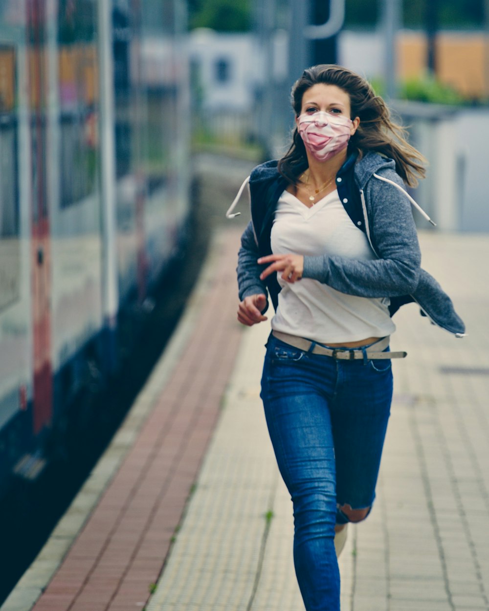 woman in gray long sleeve shirt and blue denim jeans standing on sidewalk during daytime