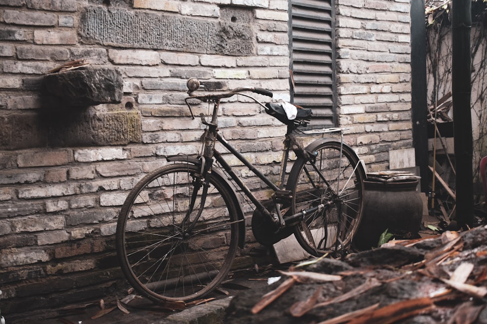 black commuter bike leaning on brown brick wall