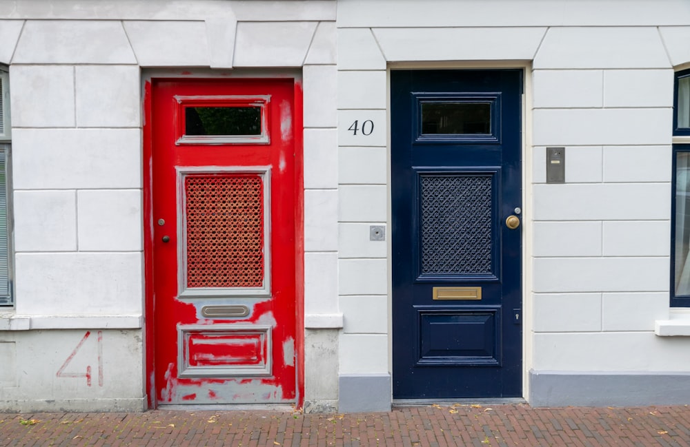 Una puerta roja y una puerta azul en un edificio blanco