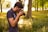 Photo of a man holding a camera, standing in a sunlit park