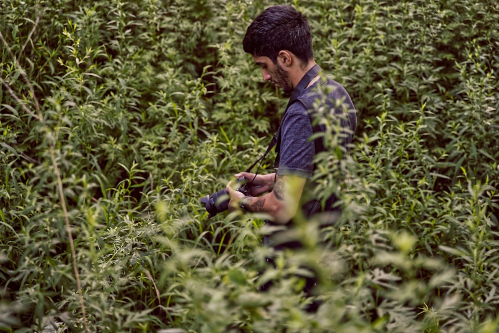 man in green shirt and black pants sitting on green grass during daytime