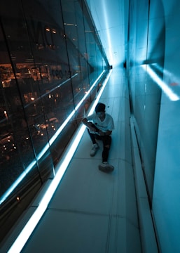 man in white t-shirt and black pants sitting on the edge of a building