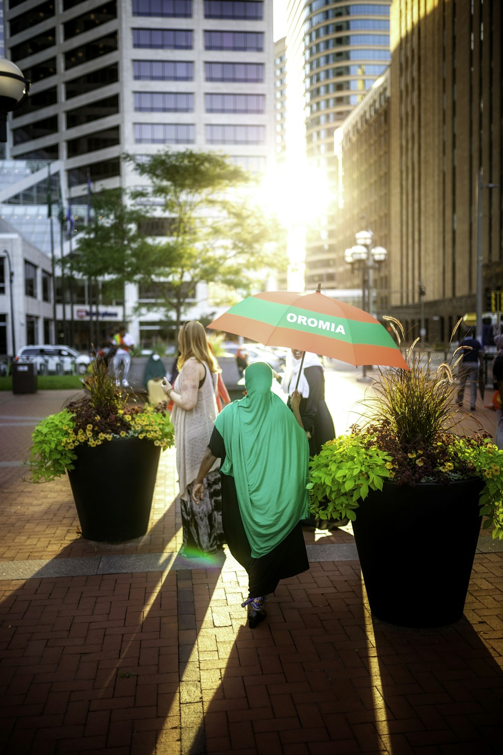 woman in green hoodie holding umbrella standing near green potted plant during daytime