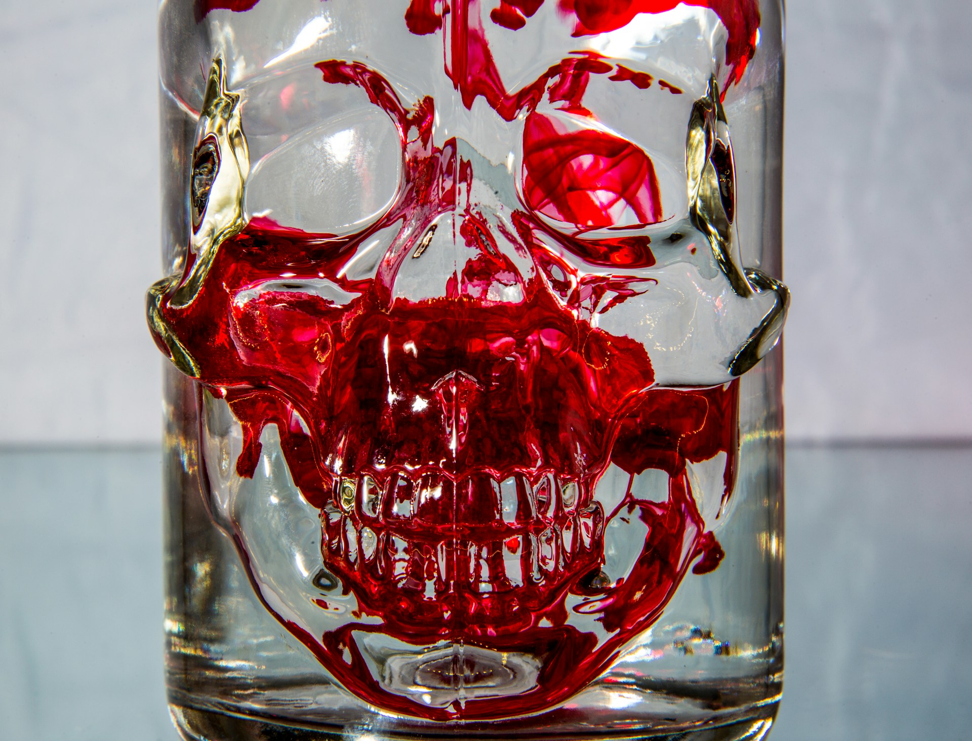 A close-up of a steaming, dark purple cocktail served in a skull-shaped glass, glowing faintly under the cafe's haunting lights.