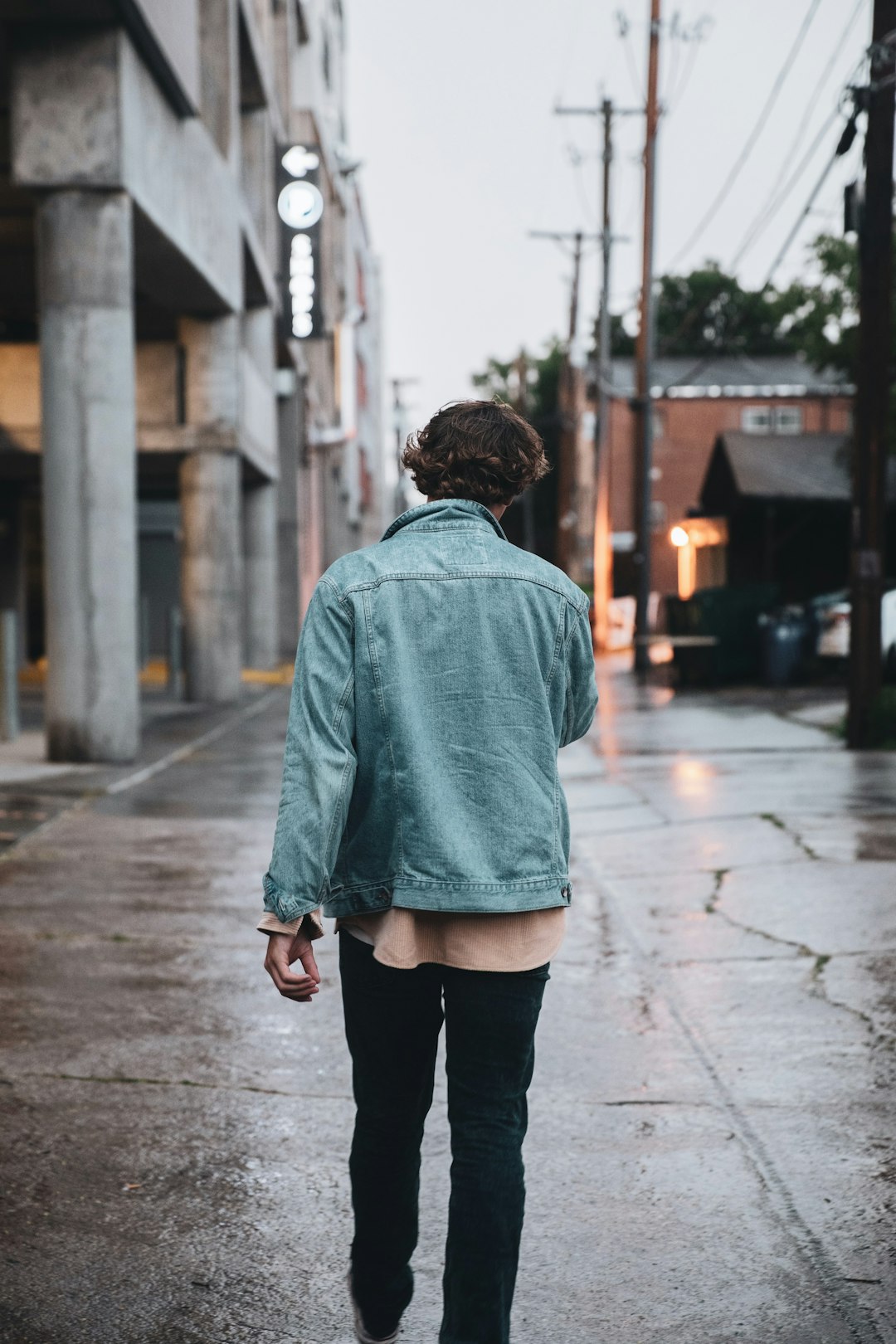man in green hoodie standing on sidewalk during daytime