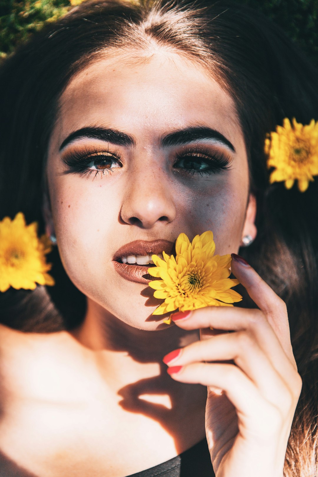 woman holding yellow flower in front of her face