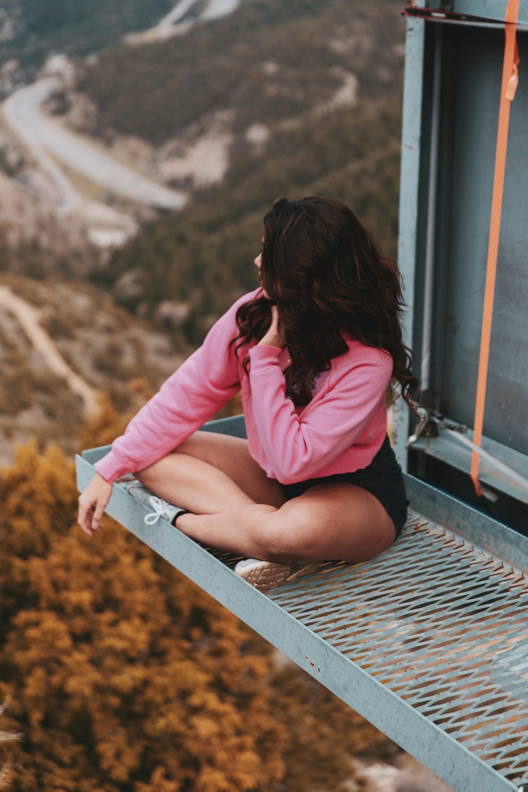 woman in pink long sleeve shirt sitting on train rail during daytime