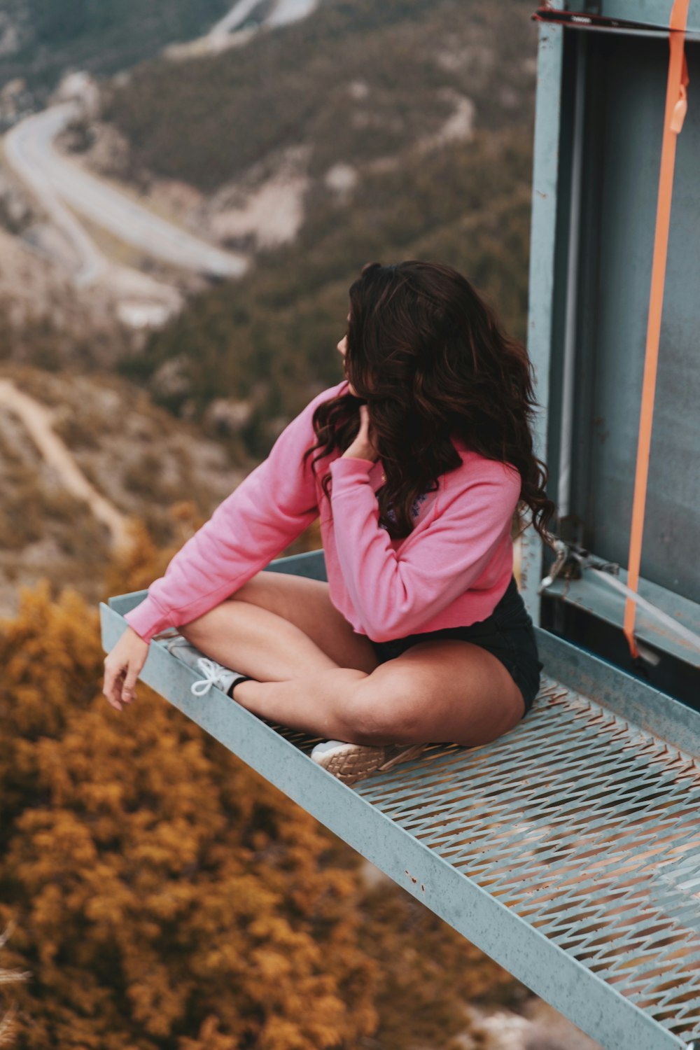 donna in camicia rosa a maniche lunghe seduta sulla rotaia del treno durante il giorno