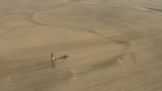 A professional photo of sprawling farmland with modern agricultural machinery in action.