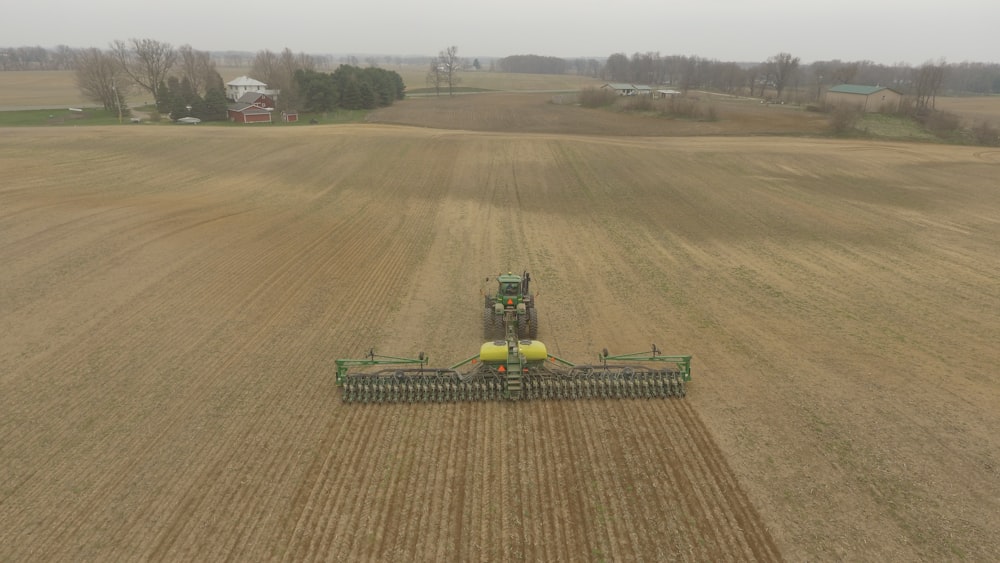 green and yellow tractor on brown field during daytime