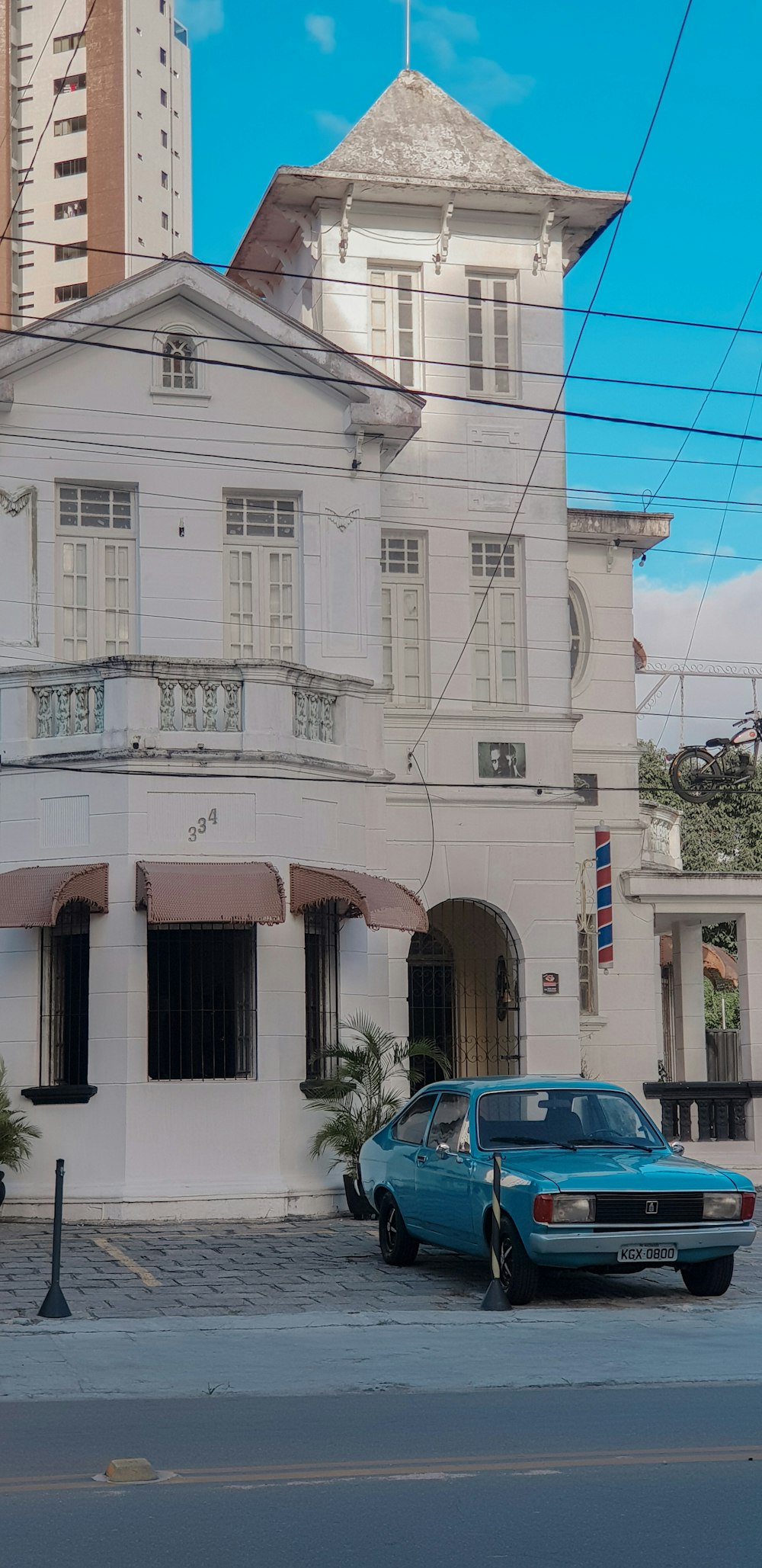 blue car parked beside white concrete building during daytime