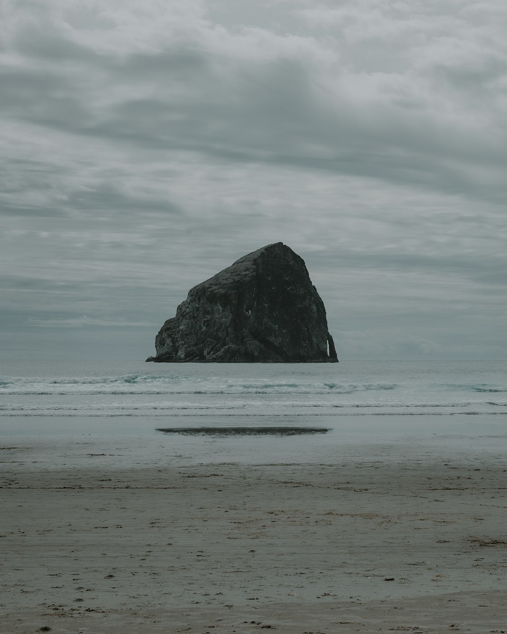 black rock formation on sea under white clouds during daytime