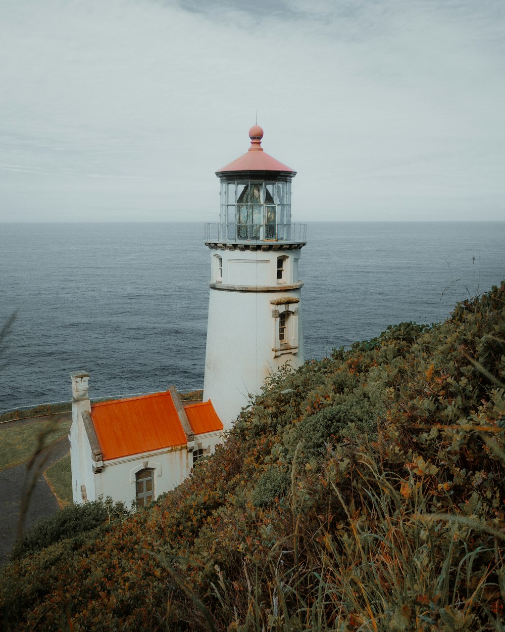 Faro de hormigón blanco y marrón cerca del cuerpo de agua durante el día