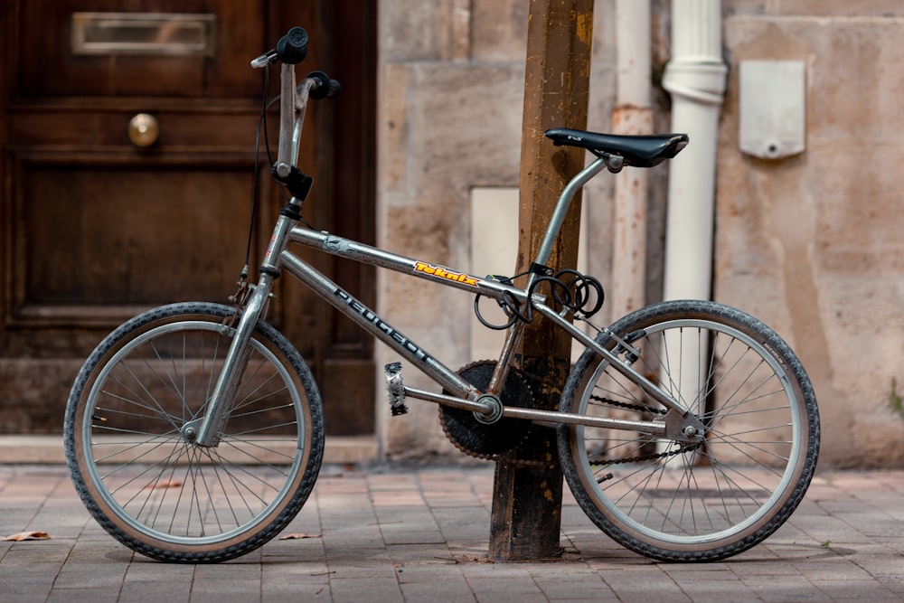 black and blue mountain bike parked beside brown wooden fence during daytime