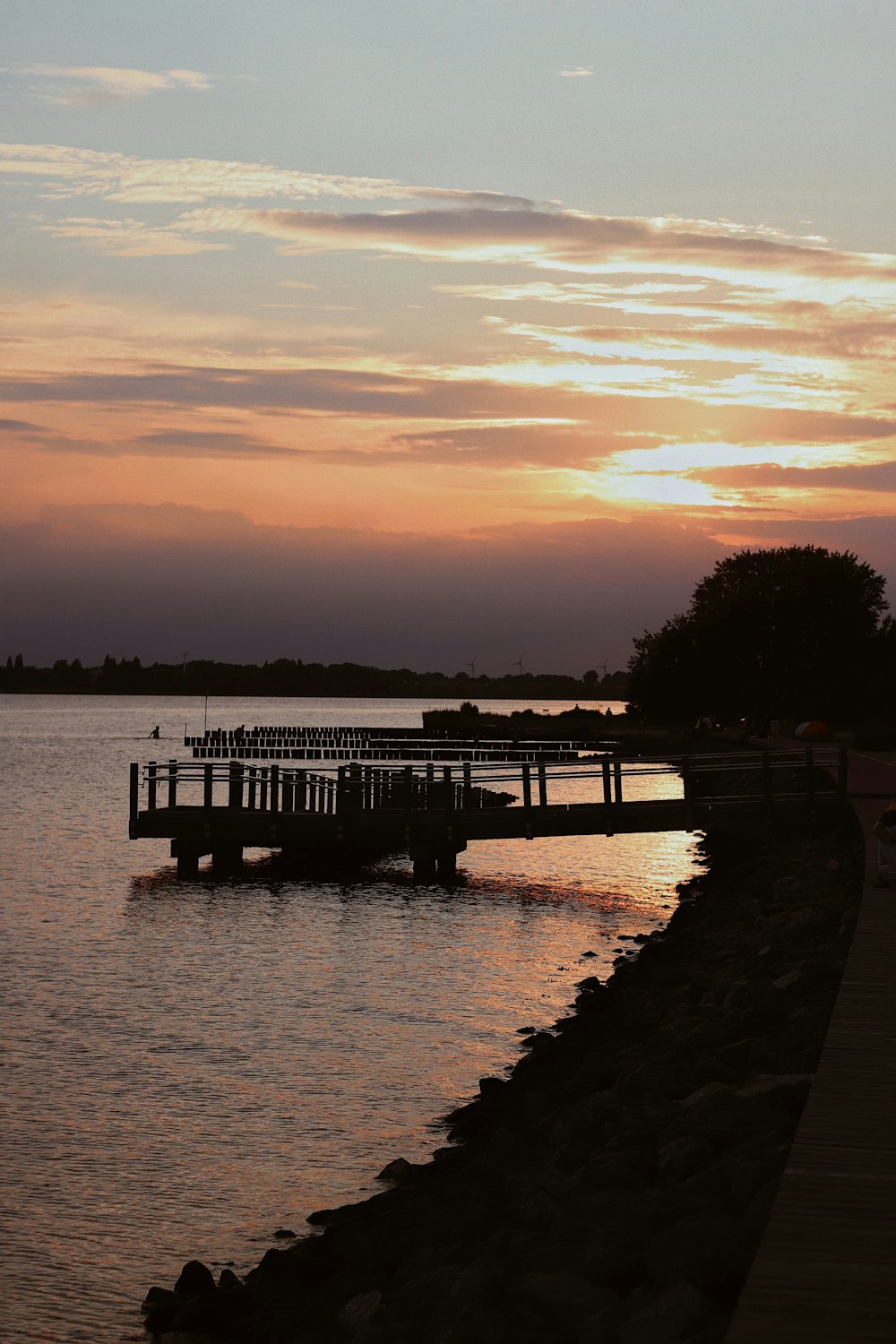 silhouette of dock on body of water during sunset