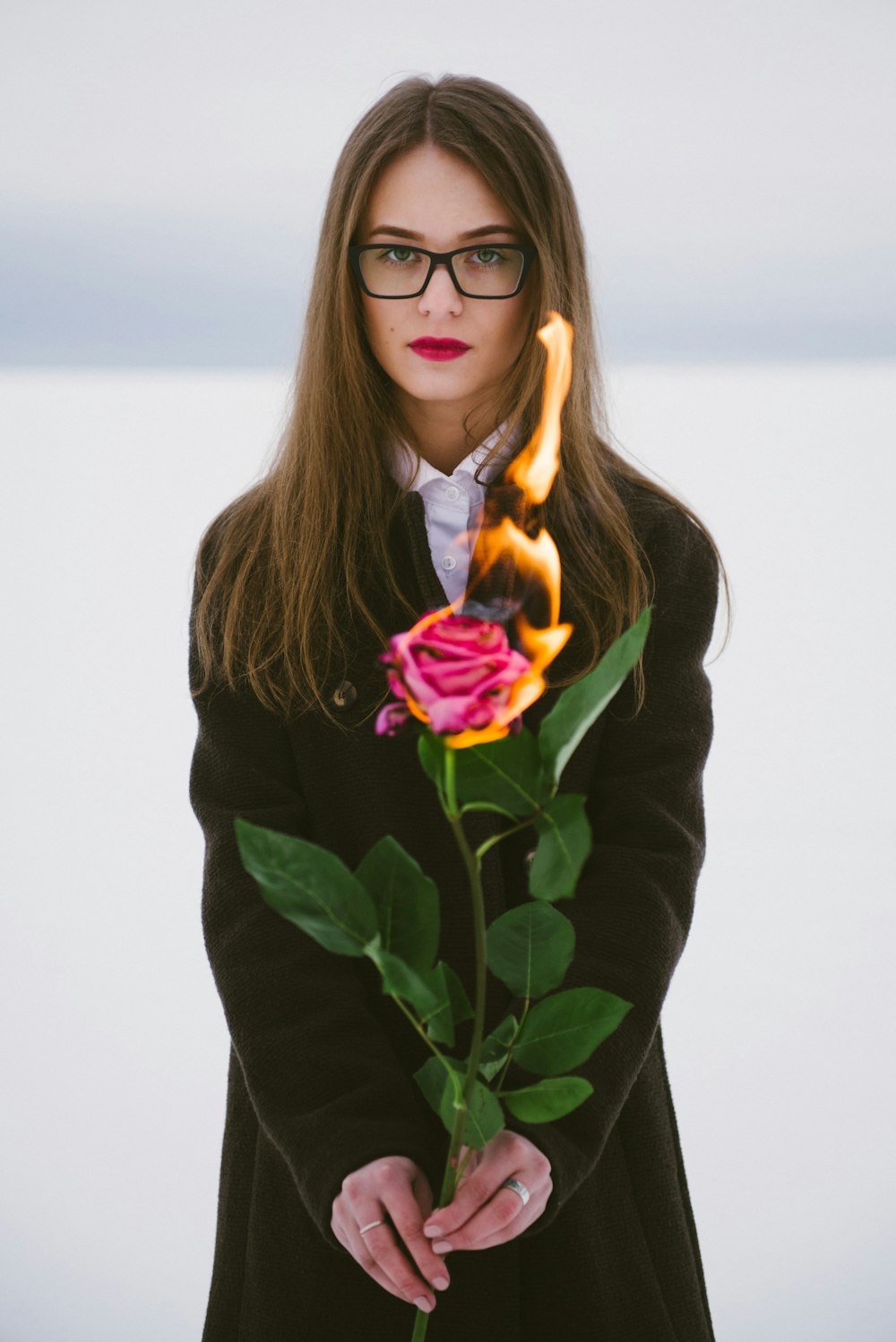 donna in camicia nera a maniche lunghe che tiene il fiore viola