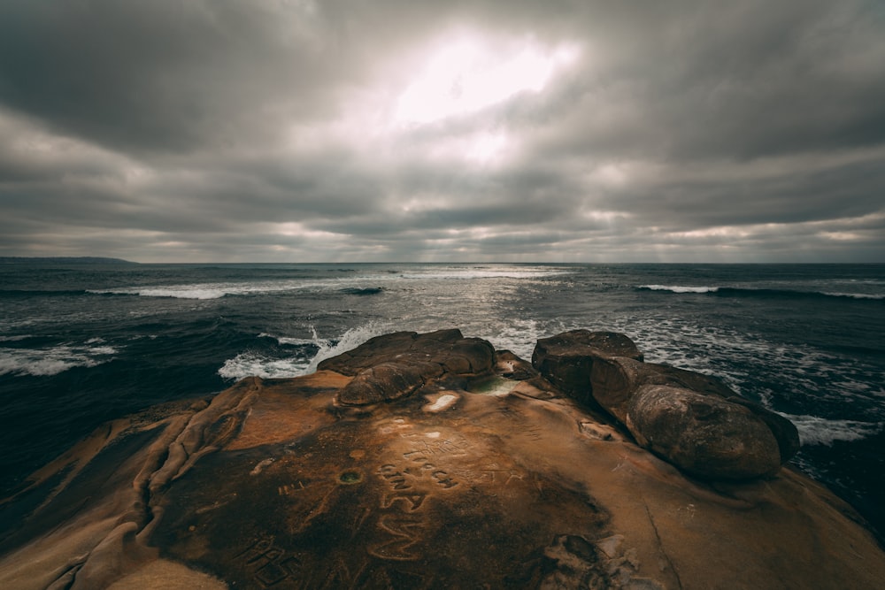 brown rocky shore under gray cloudy sky