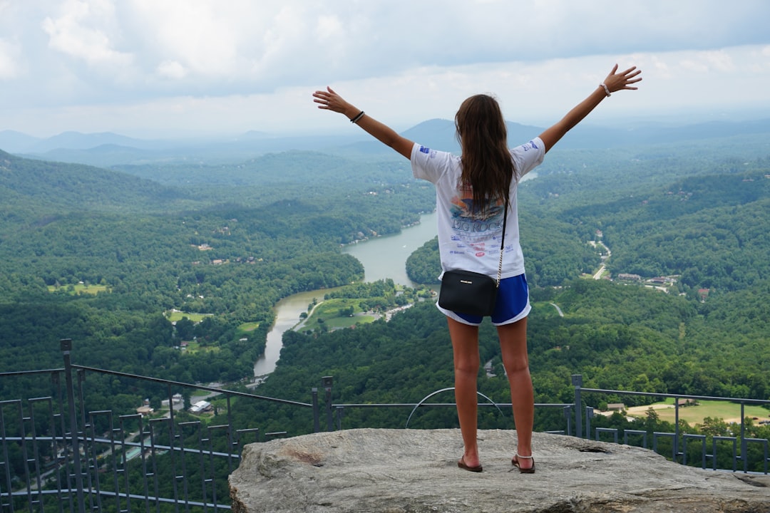 woman in white long sleeve shirt and blue shorts standing on rock formation during daytime