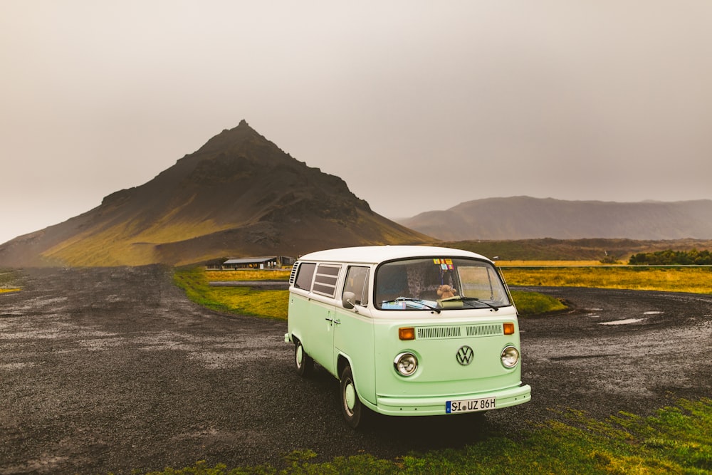 Volkswagen T-2 bianca sul campo di erba verde vicino alla montagna durante il giorno