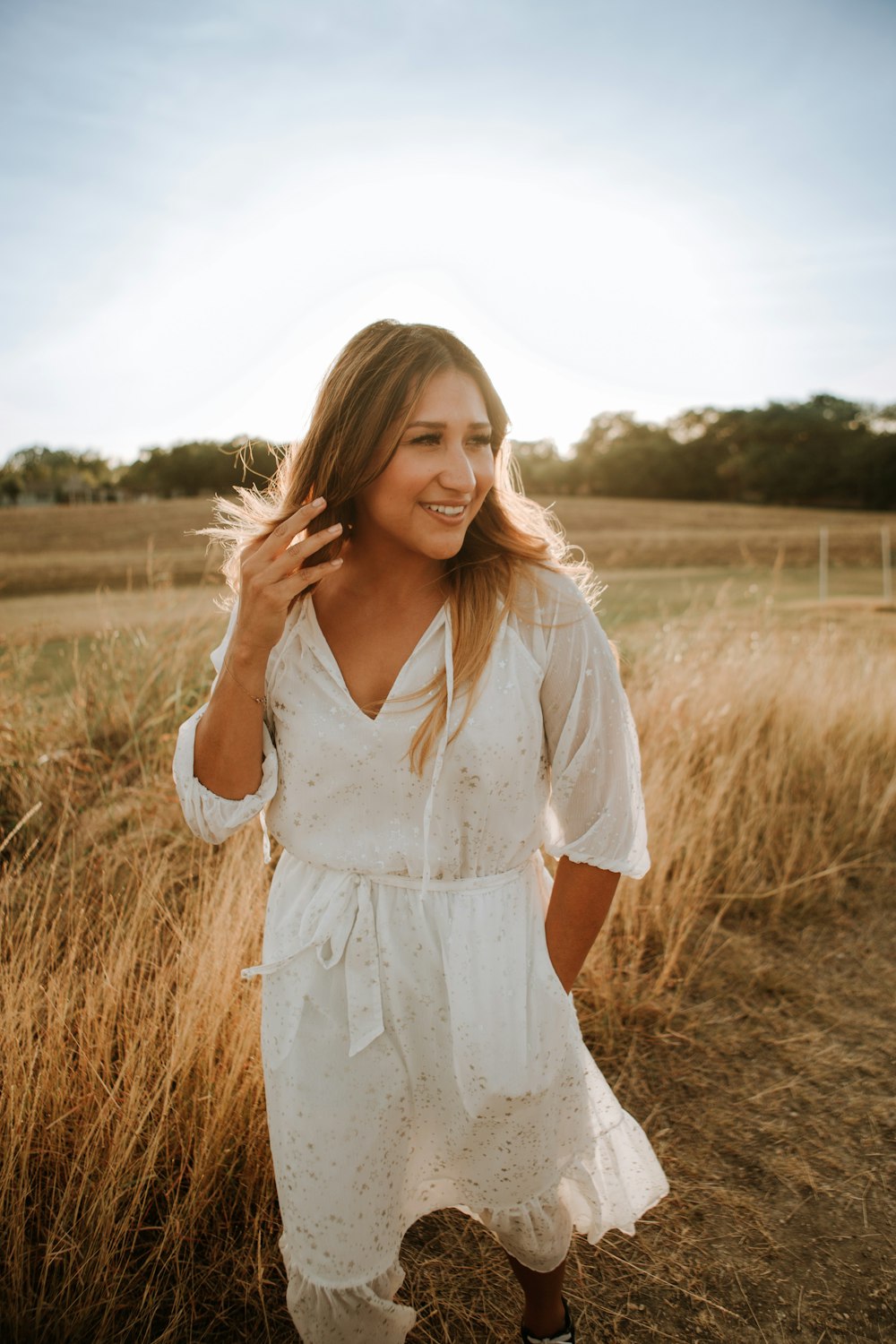 woman in white dress standing on brown grass field during daytime