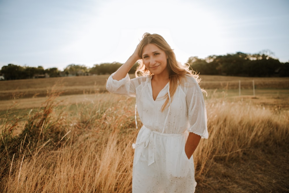 woman in white dress standing on brown grass field during daytime