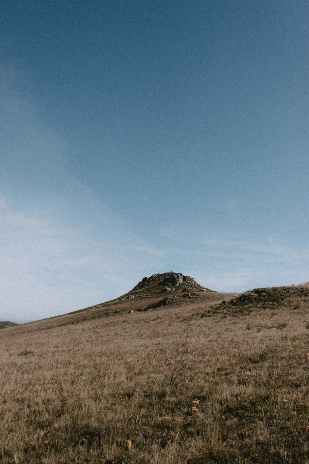 brown grass field and mountain under blue sky during daytime