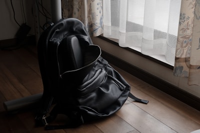 Sunlight filtering through a window onto a neat row of small backpacks and shoes by the door.