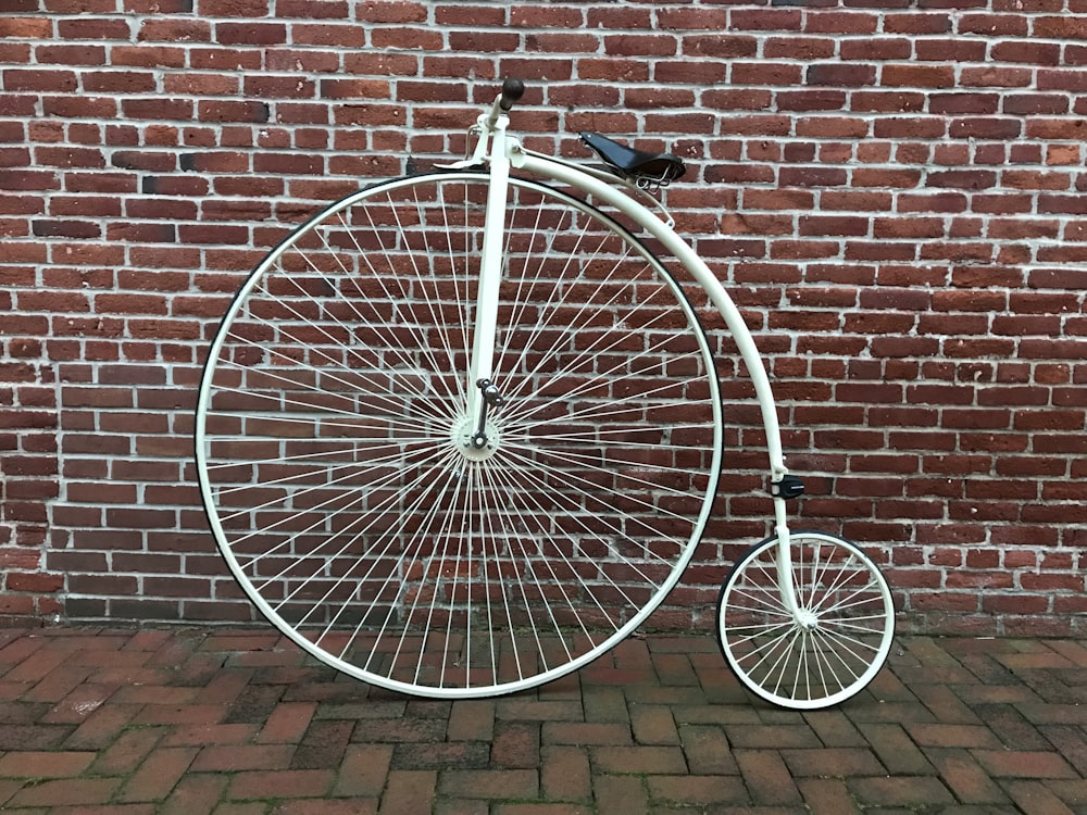 black bicycle leaning on brown brick wall