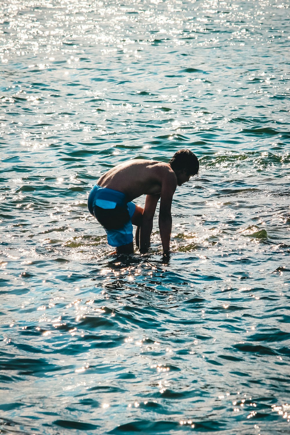 man in blue shorts holding woman in blue bikini on water during daytime