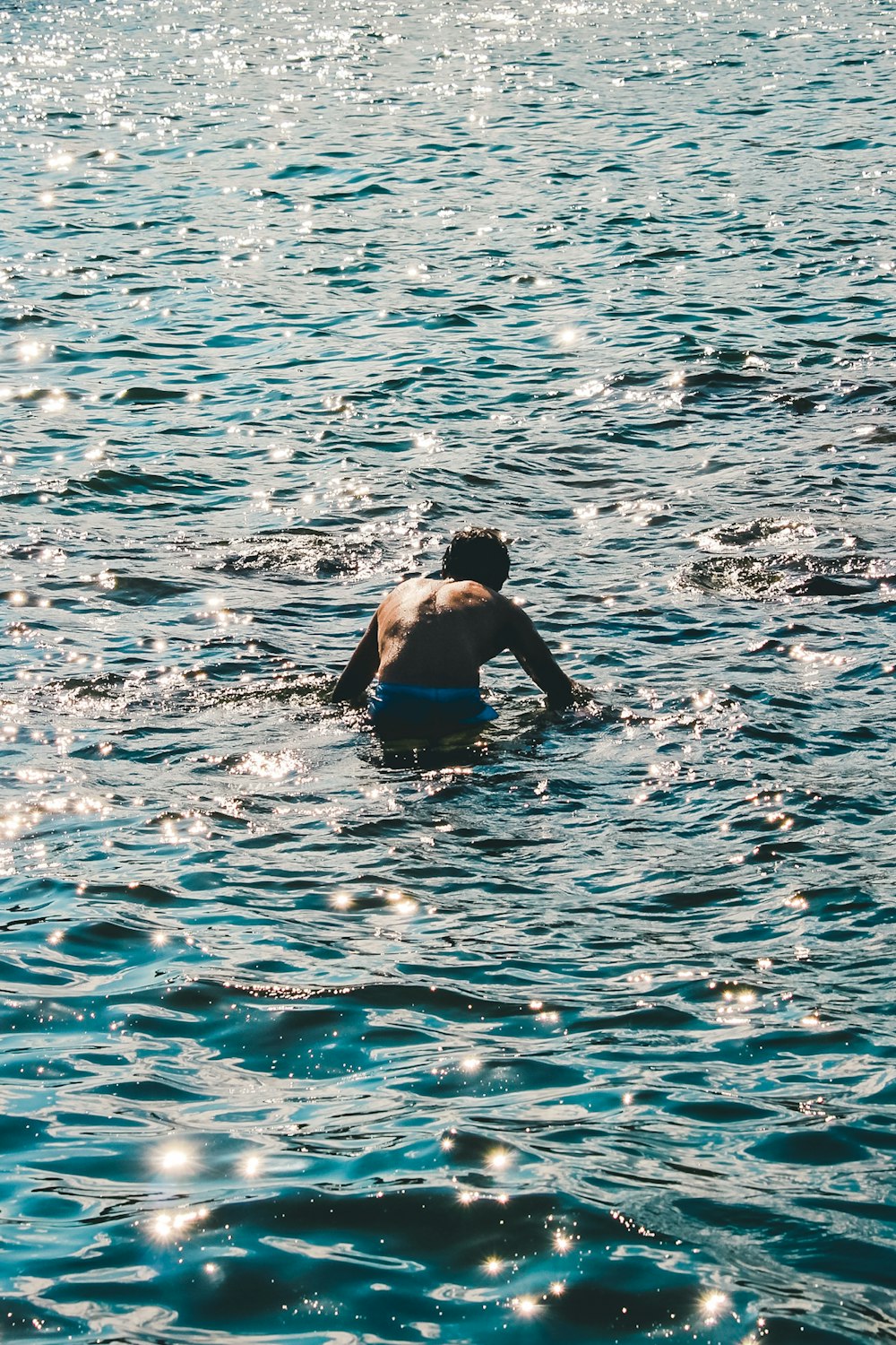 man in blue shorts swimming on water during daytime